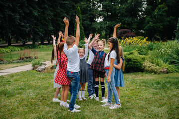 Fototapeta premium A group of children run around, have fun and play as a larger team in the summer in the Park. Happy childhood