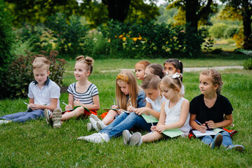 Fototapeta premium A teacher teaches a class of children in an outdoor Park. Back to school, learning during the pandemic