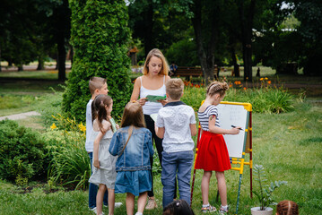 Fototapeta premium A teacher teaches a class of children in an outdoor Park. Back to school, learning during the pandemic