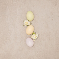 Flat lay creative spring composition with eggs and white roses on beige stone background. Top view, contemporary style, minimal Easter concept