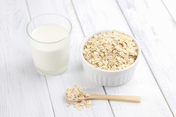A glass of oatmeal milk on a white wooden table. An alternative to cow's milk, ideal for vegans and vegetarians
