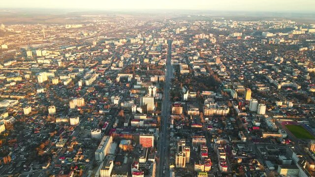 Aerial drone view of Chisinau downtown at sunset. Multiple buildings, trees, parks, road with mooving cars. Moldova
