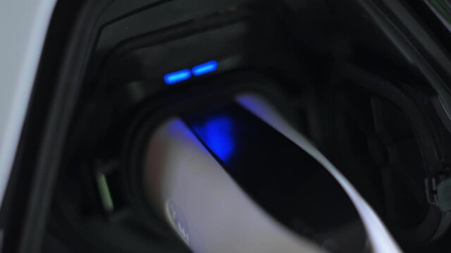 Plugged charger into an electric car, blue flickering light in the socket