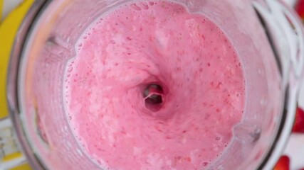 Strawberry and banana milkshake blended in blender with splashes. top view. slow motion. Healthy drink concept
