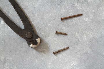 Old rusty pliers and nails on a stone background. View from above