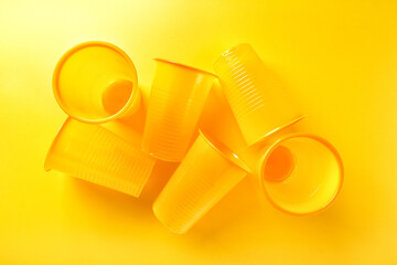 group of empty disposable plastic cups on bright yellow background