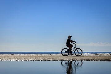 Obraz premium Solo cyclist out for a leisurely ride on an Ocean beach.