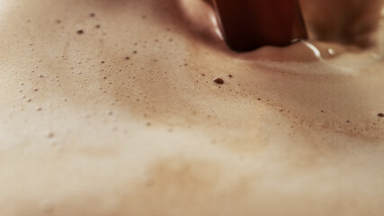 Detail of coffee drink being pour into foamy coffee drink.