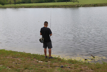 Fototapeta na wymiar Young man fishing at Big Bend Lake in Des Plaines, Illinois