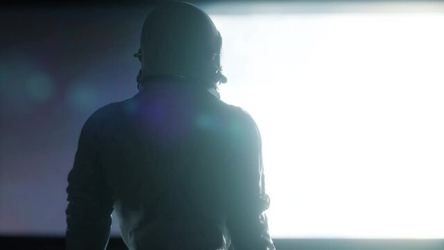 Alone astronaut looking at the huge illuminator of an unknown spaceship interior