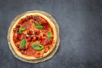Food concept. Delicious baked pepperoni pizza on parchment. Top view and dark background.