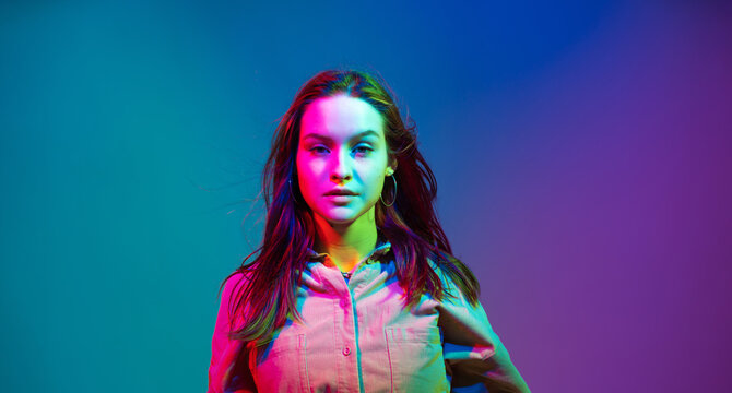 Headshot of beautiful young girl in colourful neon studio light, woman beauty portrait with copy space