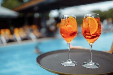 Glass of delicious cocktail near swimming pool, space for text. Refreshing drink