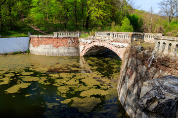 Old arched brick bridge across a pond in Sharovka Palace park in in Kharkov region, Ukraine