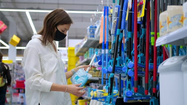 Woman buyer in mask choosing a floor mop