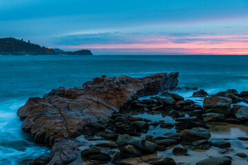 Rocky Sunrise at the seaside with cloud cover and headland