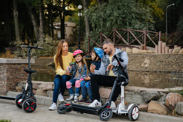 A large happy family rides Segways and electric scooters in the Park on a warm autumn day during sunset. Family vacation in the Park.