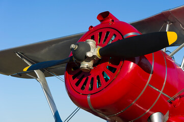 Retro plane with propeller, vintage biplane with red fuselage, old aircraft detail, civil aviation concept, blue sky on background