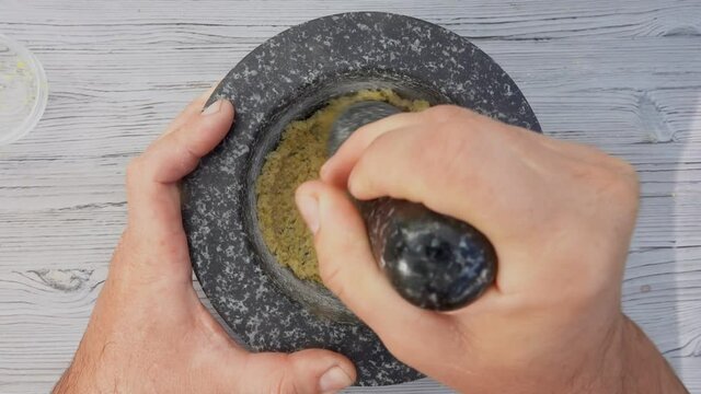 Male hands are grinding sea salt, lemon and brown sugar in the mortar