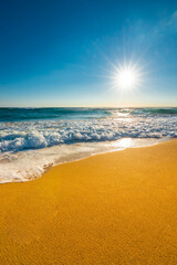 Ocean water flowing over rocks and beach with golden sunrise