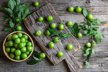 Fresh ripe organic green plums or greengage in bowl on rustic background, heap of summer fruits concept