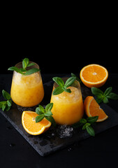 Fototapeta na wymiar Cold summer orange lemonade with mint and ice in a glass. Copy Space for text