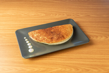 Image of Venezuelan corn cachapa stuffed with cheese on black plate