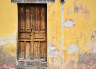 Puerta de madera color cafe de una casa de color amarillo en las calles de  Antigua Guatemala.