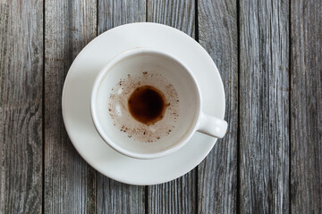 Empty cup with coffee leftovers on wooden table, closeup