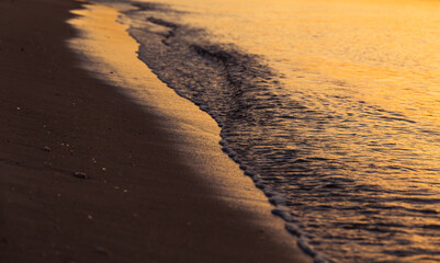 Close up of small waves crushing the shore of Poetto beach at sunrise