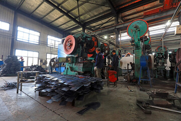 Workers in the steel shovel blanking production line busy in a hardware tool manufacturing company
