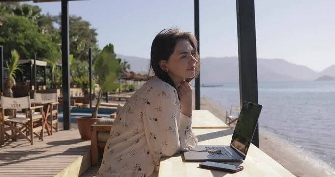 Woman Working on Laptop in Coastline in Summer Sunny Day. Female Freelancer, Digital Nomad or Businesswoman Use Computer on Holiday. COVID-19 Distance Work Concept.