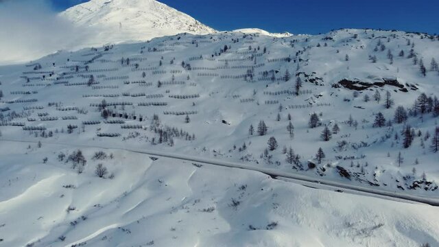 The pass road to the Simplon Pass in Switzerland. The Simplon Pass is the border between Italy and Switzerland. The landscape is snow covered and avalanche protection devices are on the mountain