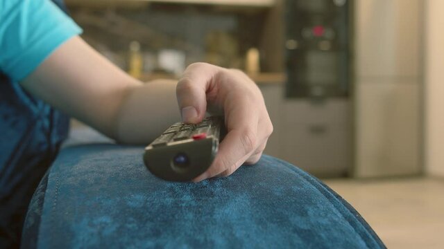 Man picks up a remote control and switches channels, presses buttons, camera movement