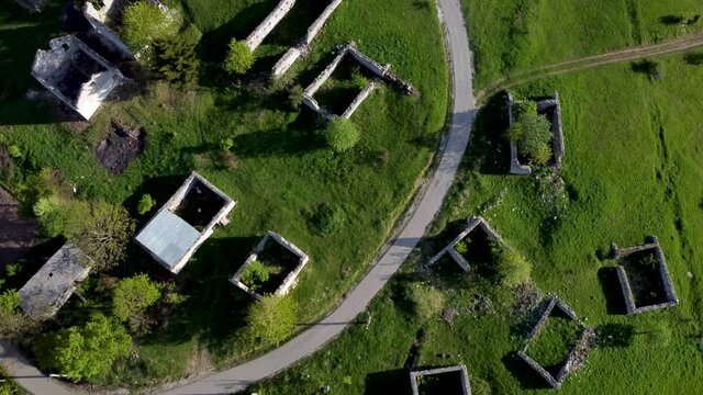 Ruined and damaged houses in village as war aftermath. Aerial drone view of homes destroyed and burned in war by artillery. Abandoned buildings. Houses ruins. 