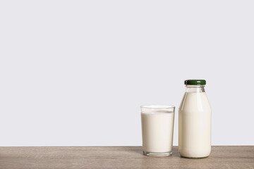 Bottle of milk and a glass on rustic table .