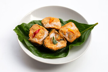 Thai streamed fish curry in banana leaves on white.