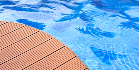 Swimming pool with wooden deck floor.  Summer background concept
