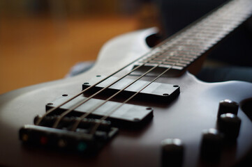 Fototapeta premium Closeup shot of a smooth body, pickups, bridge, knobs and strings of a bass guitar musical instrument with backlight
