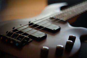 Closeup shot of a smooth body, pickups, bridge, knobs and strings of a bass guitar musical...