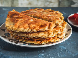 Hot homemade pasties on a ceramic plate with a pattern, close-up