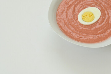 Close up of spanish cordobes gazpacho samorejo plate with boiled egg on white plate over white background