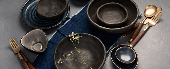 Table setting with a black and blue plates on gray background. Minimalism concept.