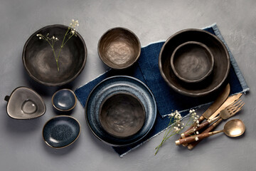 Table setting with a black and blue plates on gray background. Minimalism concept.