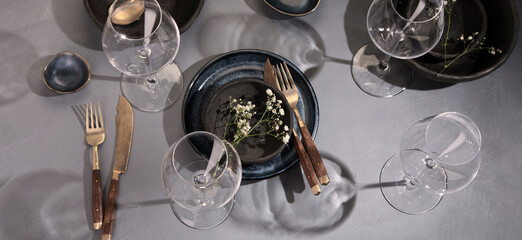 Table setting with a black and blue plates on gray background. Minimalism concept.
