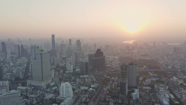 Aerial view over Bangkok city and Chao phraya river and Tak-sin bridge Saphan Taksin BTS train station in the morning with morning sun rise.
