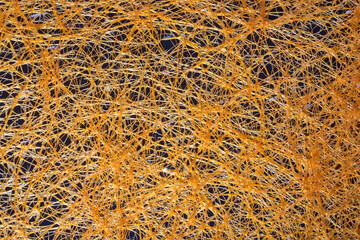 Abstract background of yellow plastic threads on a dark background