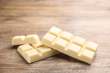 Pieces of tasty sweet chocolate on wooden table, closeup