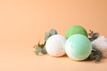 Colorful bath bombs, salt and eucalyptus branches on beige background, space for text