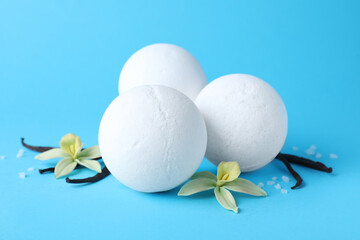 White bath bombs, vanilla sticks and flowers on light blue background